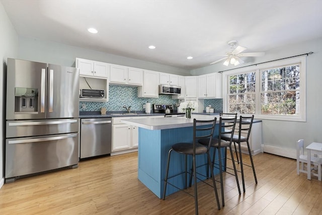 kitchen with stainless steel appliances, light hardwood / wood-style flooring, white cabinets, and a breakfast bar