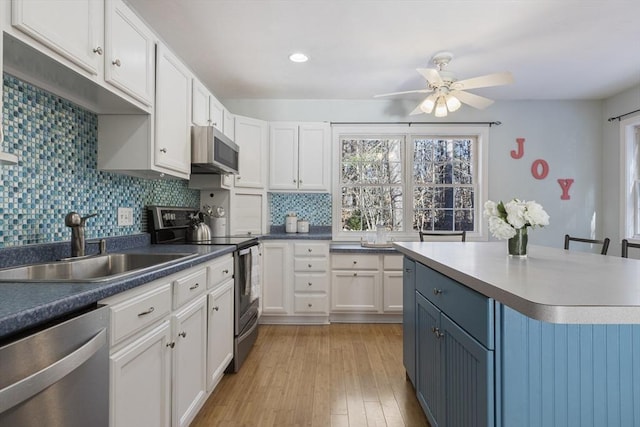 kitchen with a breakfast bar, sink, white cabinetry, light hardwood / wood-style flooring, and appliances with stainless steel finishes