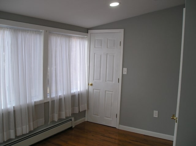 empty room with lofted ceiling, a baseboard radiator, and dark hardwood / wood-style floors