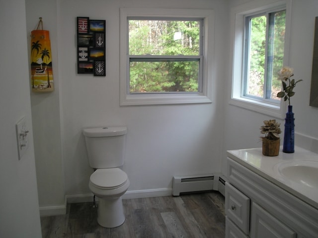 bathroom featuring toilet, a baseboard heating unit, a healthy amount of sunlight, and vanity