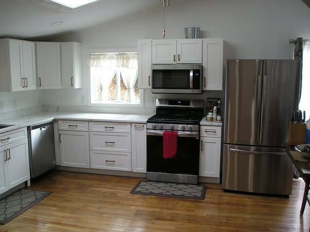 kitchen featuring light hardwood / wood-style flooring, white cabinets, stainless steel appliances, and vaulted ceiling