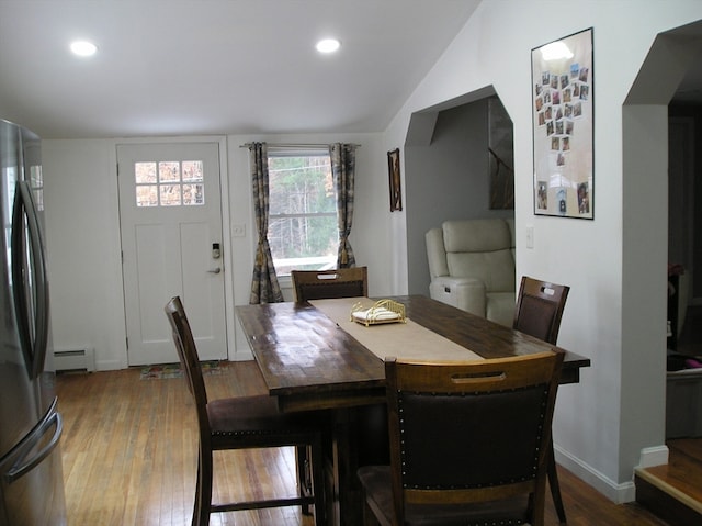 dining area with hardwood / wood-style flooring, baseboard heating, and vaulted ceiling