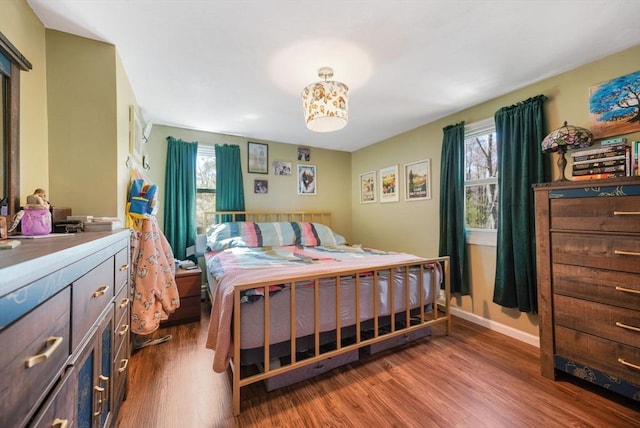 bedroom with baseboards, multiple windows, and wood finished floors