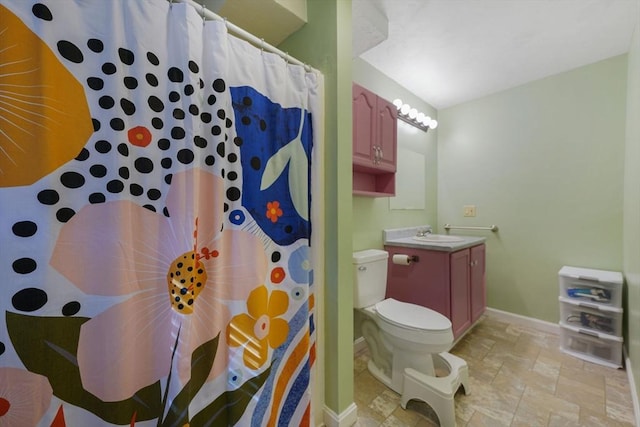 full bath featuring a shower with curtain, stone finish floor, baseboards, vanity, and toilet