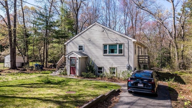 exterior space with driveway, a front yard, a storage shed, stairway, and an outdoor structure