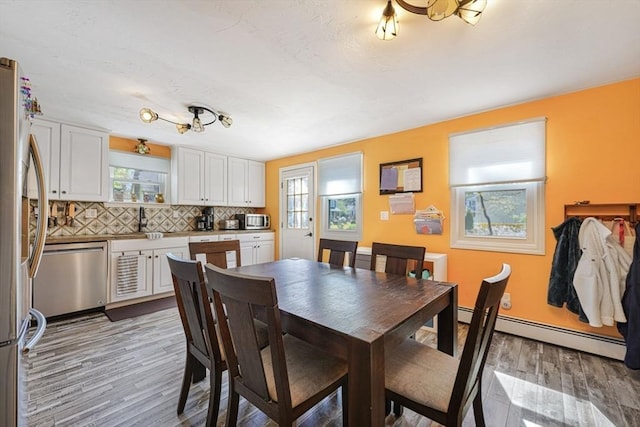 dining space featuring light wood-style flooring, a wealth of natural light, and baseboard heating
