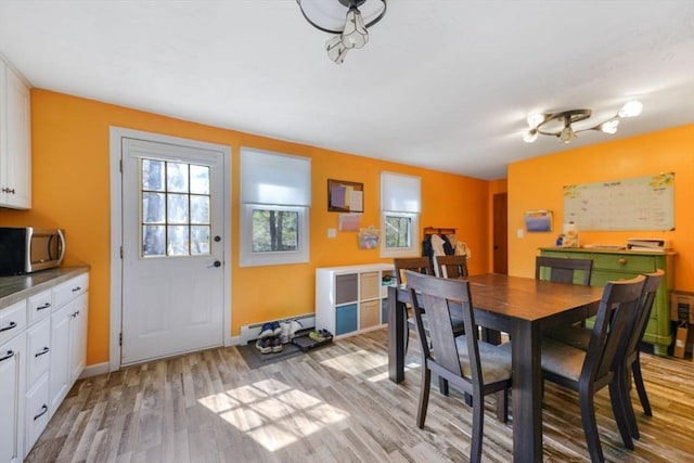 dining space featuring baseboards, light wood finished floors, and a baseboard radiator