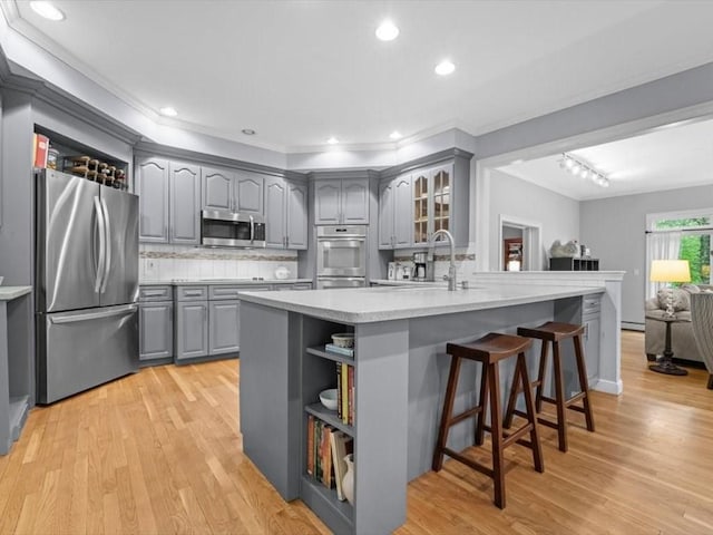 kitchen with appliances with stainless steel finishes, gray cabinetry, a sink, open shelves, and light wood-style floors
