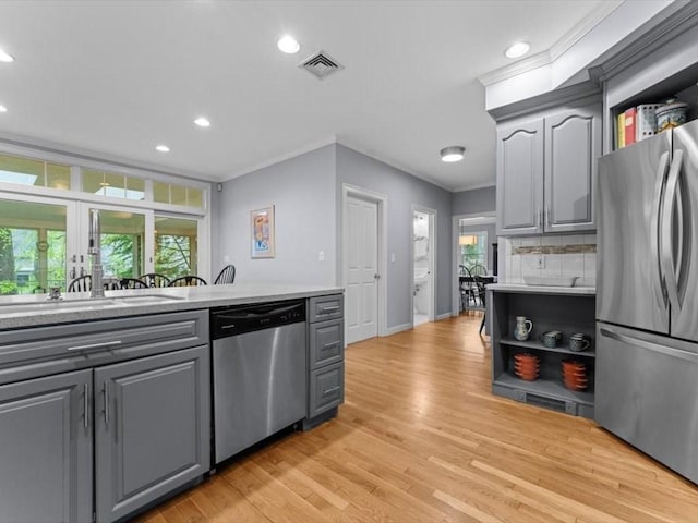 kitchen featuring appliances with stainless steel finishes, gray cabinetry, crown molding, a sink, and open shelves