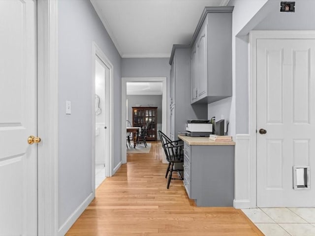 hallway with light wood-style floors and ornamental molding