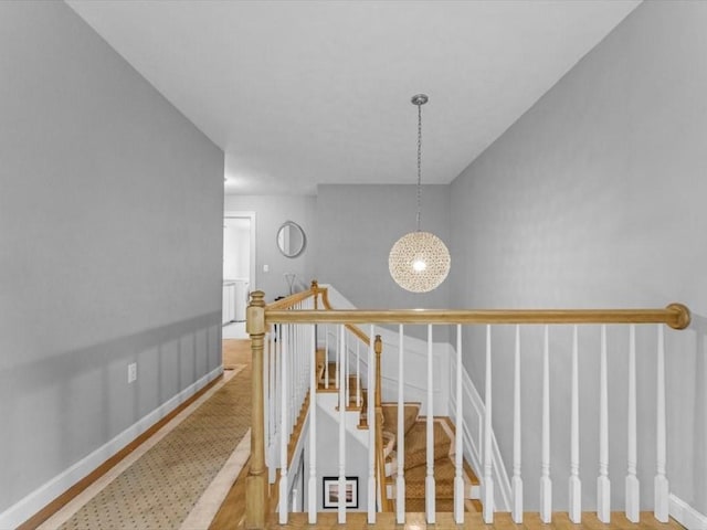 hall with baseboards and an upstairs landing