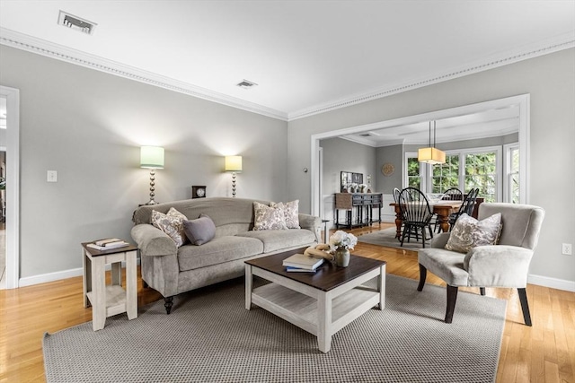 living room featuring ornamental molding, baseboards, and light wood finished floors
