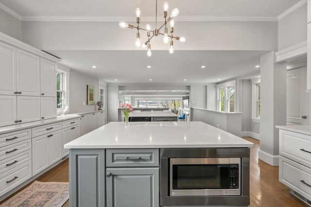 kitchen with light countertops, white cabinetry, dark wood-style flooring, and stainless steel microwave