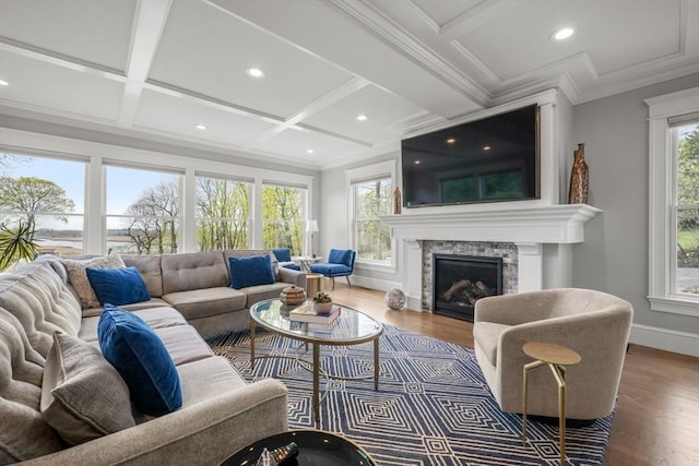living room with coffered ceiling, baseboards, a stone fireplace, and wood finished floors