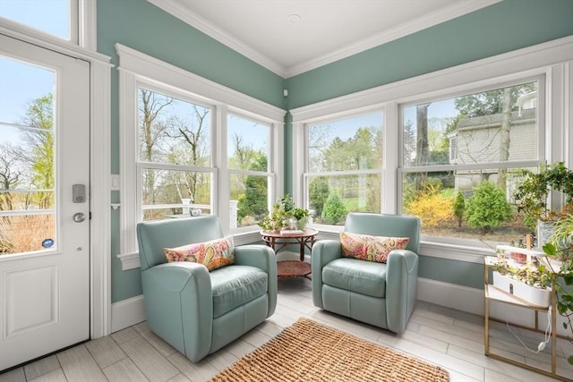sunroom / solarium featuring ornamental molding, a wealth of natural light, baseboards, and wood finished floors