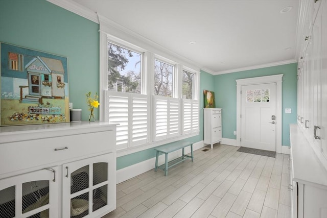 foyer entrance with crown molding and baseboards