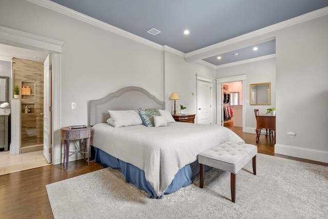 bedroom with crown molding, visible vents, wood finished floors, and a spacious closet
