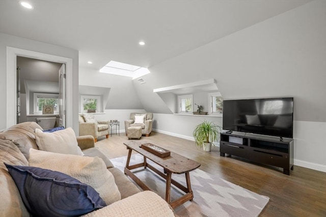 living area featuring wood finished floors, baseboards, lofted ceiling with skylight, and recessed lighting