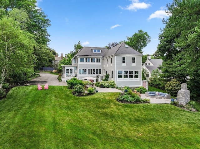 rear view of property featuring an outdoor hangout area, a patio, and a lawn