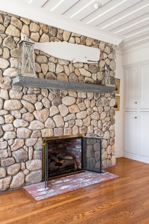 room details with a stone fireplace, hardwood / wood-style flooring, and crown molding