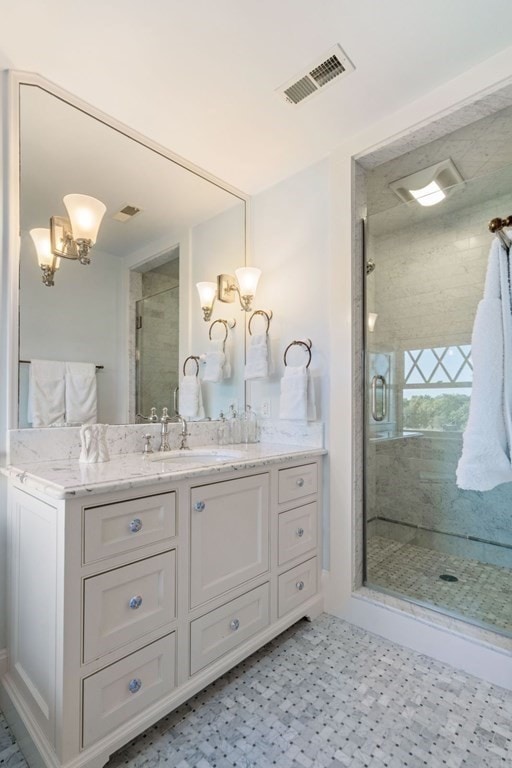 bathroom with a notable chandelier, vanity, a shower with door, and tile flooring