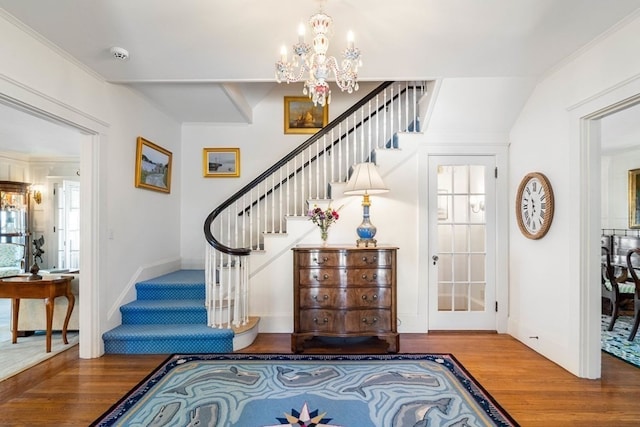 entrance foyer with ornamental molding, a notable chandelier, and wood-type flooring