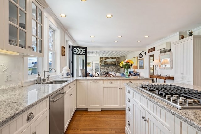 kitchen featuring appliances with stainless steel finishes, light hardwood / wood-style floors, sink, backsplash, and ornamental molding