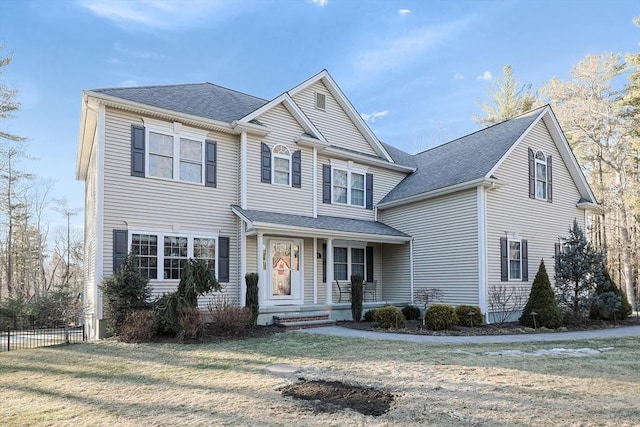 view of front facade featuring covered porch, roof with shingles, a front yard, and fence