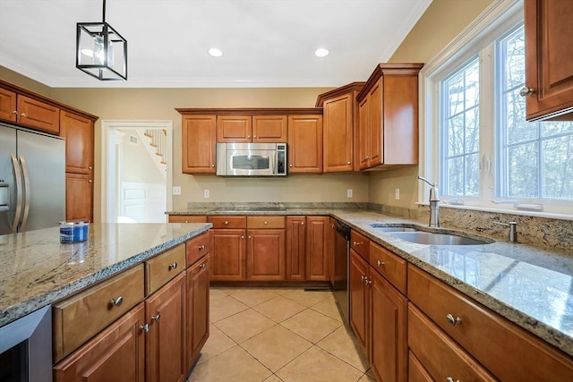 kitchen featuring pendant lighting, light stone counters, brown cabinets, appliances with stainless steel finishes, and a sink