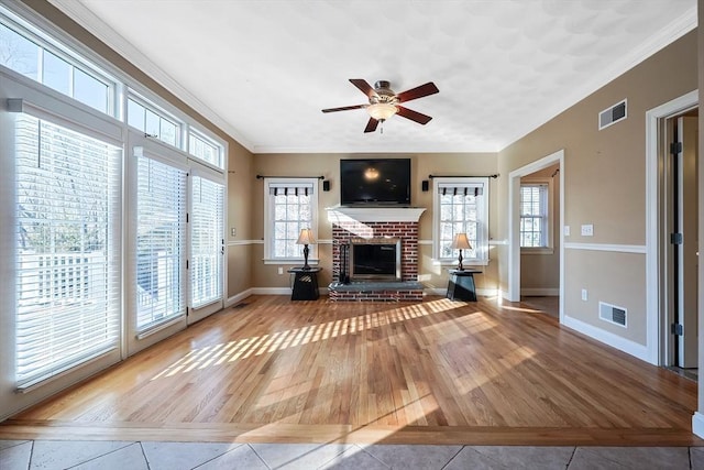 unfurnished living room with visible vents, plenty of natural light, wood finished floors, and a fireplace