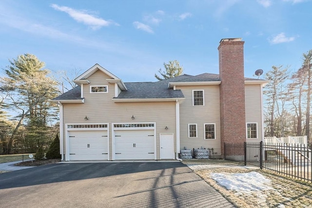 view of front of home with fence, aphalt driveway, roof with shingles, a chimney, and an attached garage