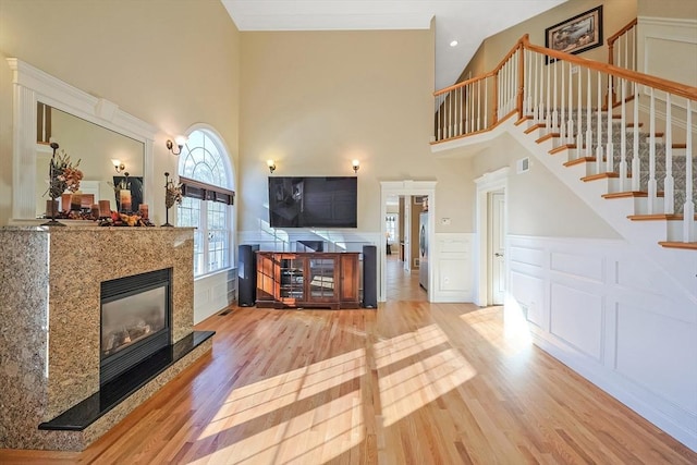 living room with a glass covered fireplace, visible vents, wood finished floors, and stairs