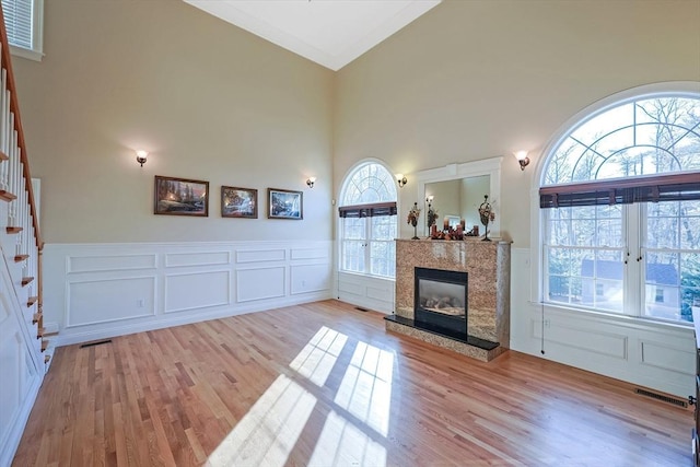 living room featuring a high end fireplace, stairway, visible vents, and wood finished floors