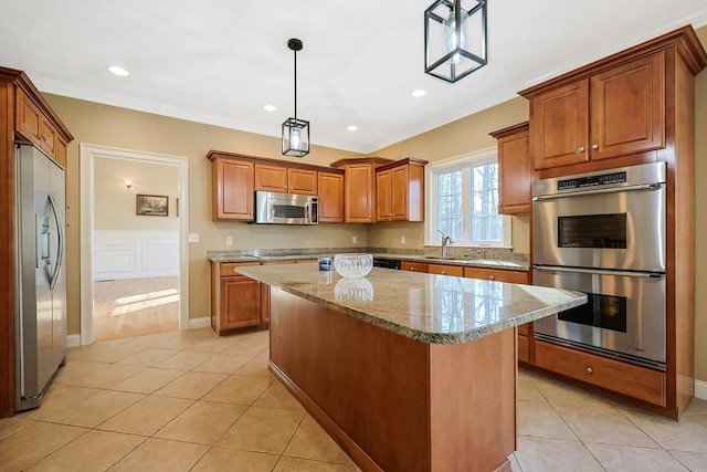 kitchen featuring brown cabinets, ornamental molding, light stone counters, appliances with stainless steel finishes, and light tile patterned floors