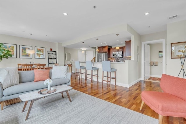 living area featuring baseboards, recessed lighting, visible vents, and light wood-style floors