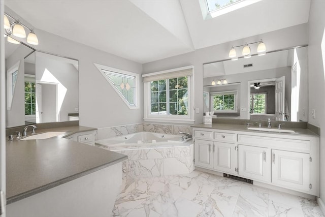267 W St, Northborough, MA 01532 - bathroom featuring two vanities, marble look tile flooring, a skylight, and a bath