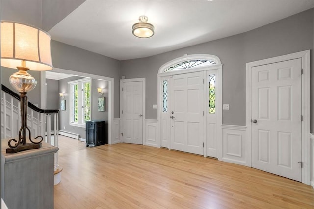 267 W St, Northborough, MA 01532 - entrance foyer with light wood-type flooring, a wainscoted wall, a baseboard radiator, a decorative wall, and stairs