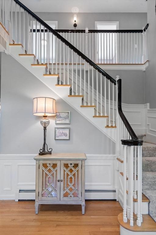 267 W St, Northborough, MA 01532 - stairway with a baseboard heating unit, a decorative wall, wood finished floors, and wainscoting