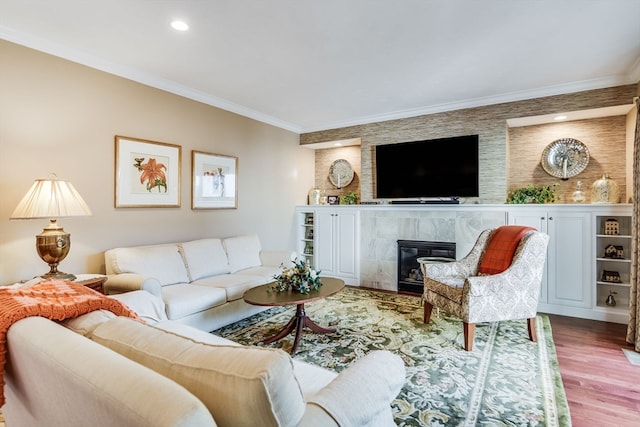 living room with wood-type flooring, crown molding, and a tiled fireplace