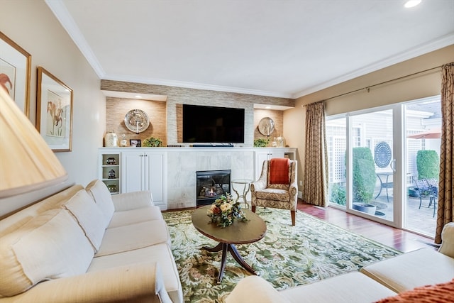 living room featuring hardwood / wood-style flooring, crown molding, and a tile fireplace