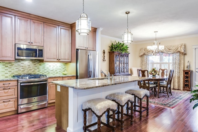 kitchen with appliances with stainless steel finishes, a center island with sink, dark hardwood / wood-style floors, and sink