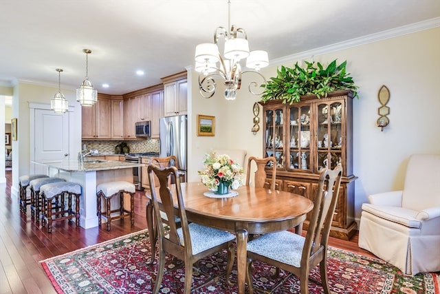 dining area with dark hardwood / wood-style flooring, crown molding, and an inviting chandelier