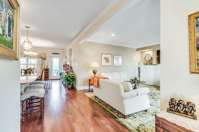 living room with hardwood / wood-style floors, crown molding, and an inviting chandelier