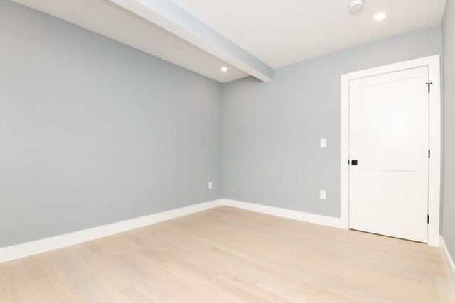 unfurnished room with beamed ceiling and light wood-type flooring