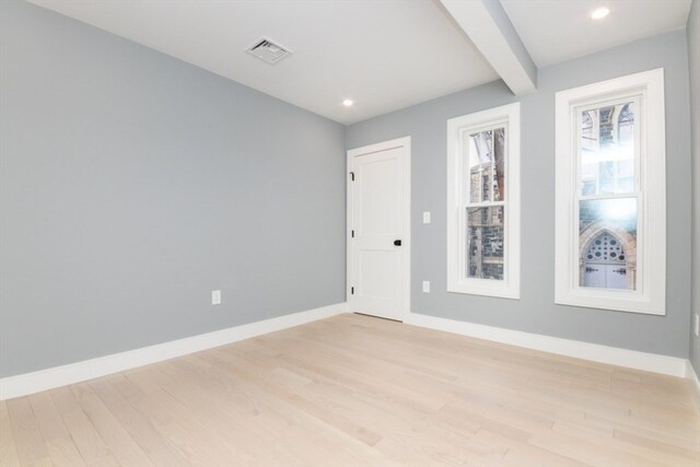 unfurnished room featuring light hardwood / wood-style flooring and beam ceiling