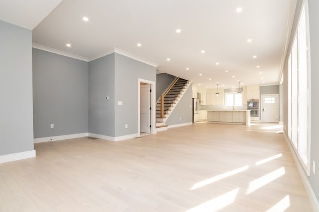 unfurnished living room with ornamental molding and light wood-type flooring