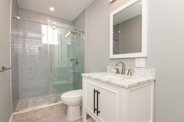 bathroom featuring vanity, toilet, a shower with shower door, and tile patterned flooring