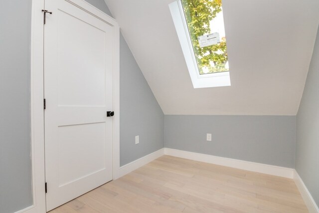 bonus room with vaulted ceiling with skylight and light hardwood / wood-style flooring