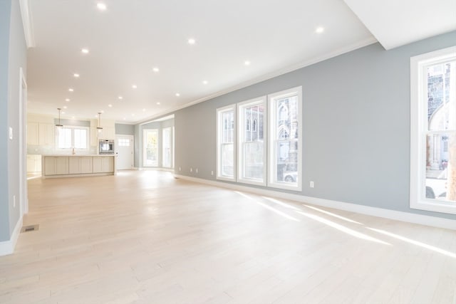 unfurnished living room featuring light hardwood / wood-style flooring and crown molding