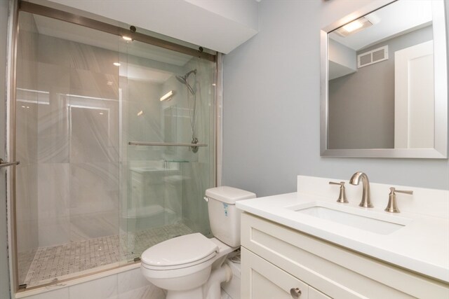 bathroom with toilet, vanity, and a shower with door